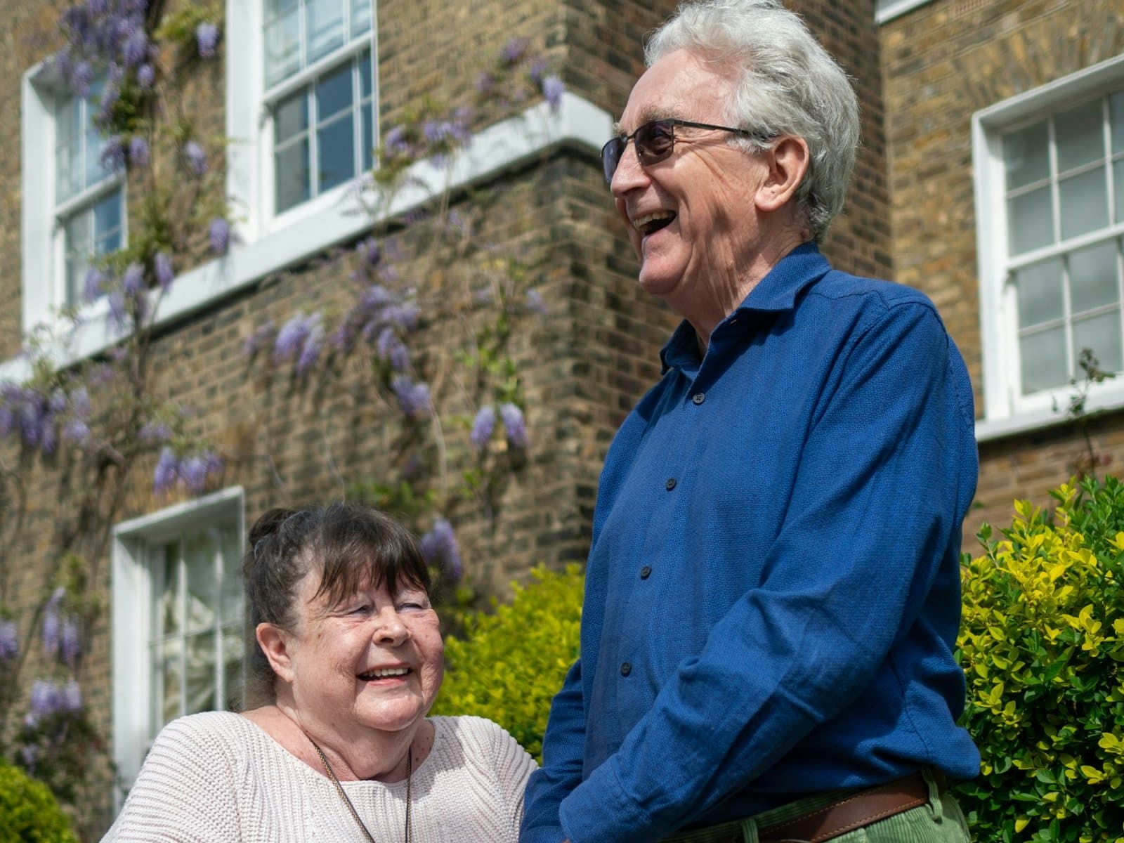 A couple in their seventies outside their brick terraced house