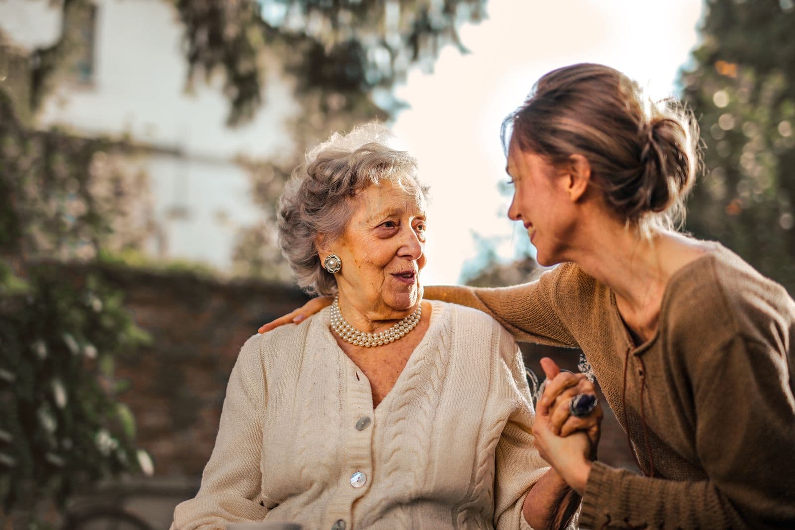 A daughter in her fifties greeting her mother in the garden