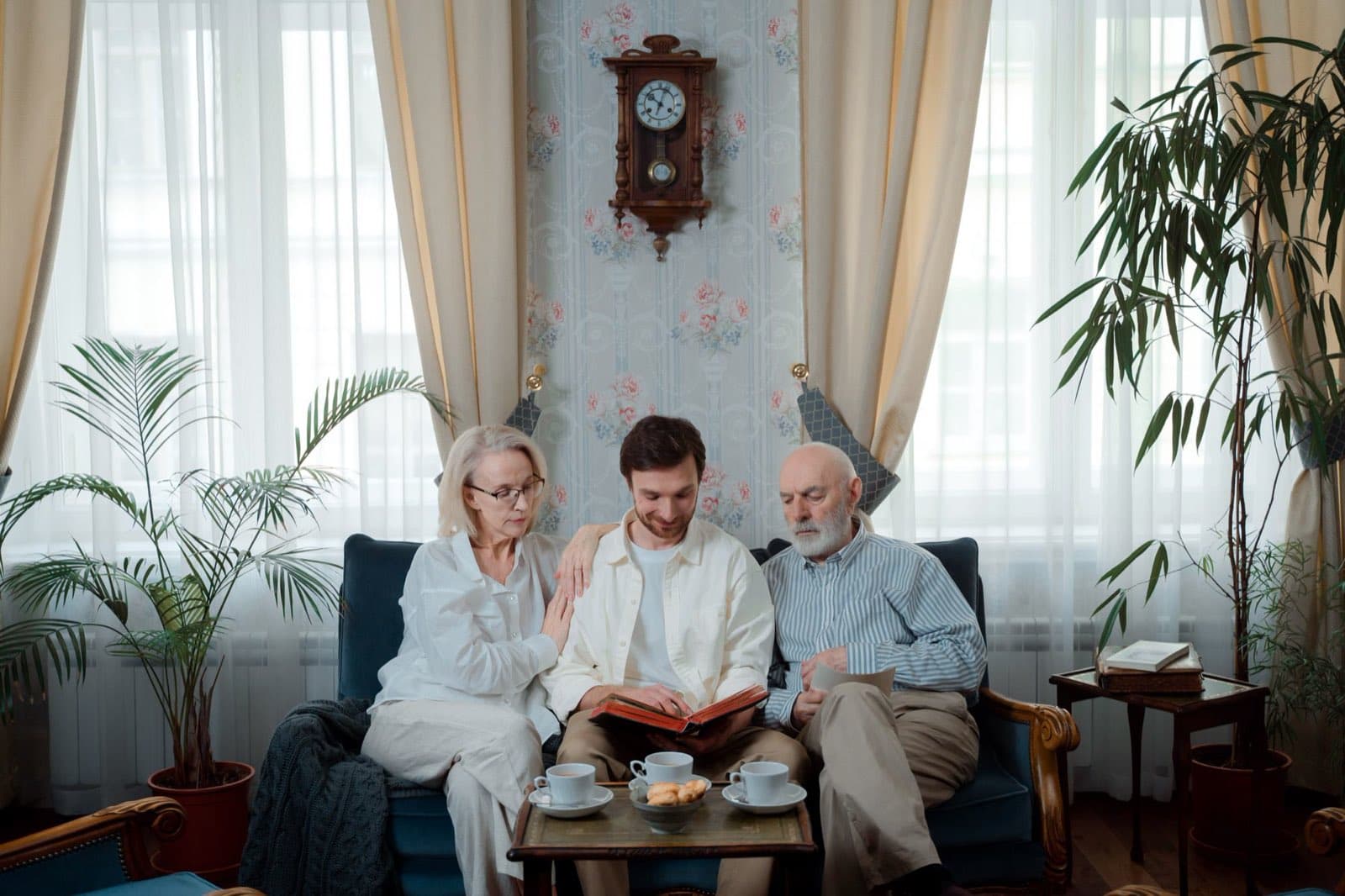 A couple in their seventies looking through a photo album with their adult son